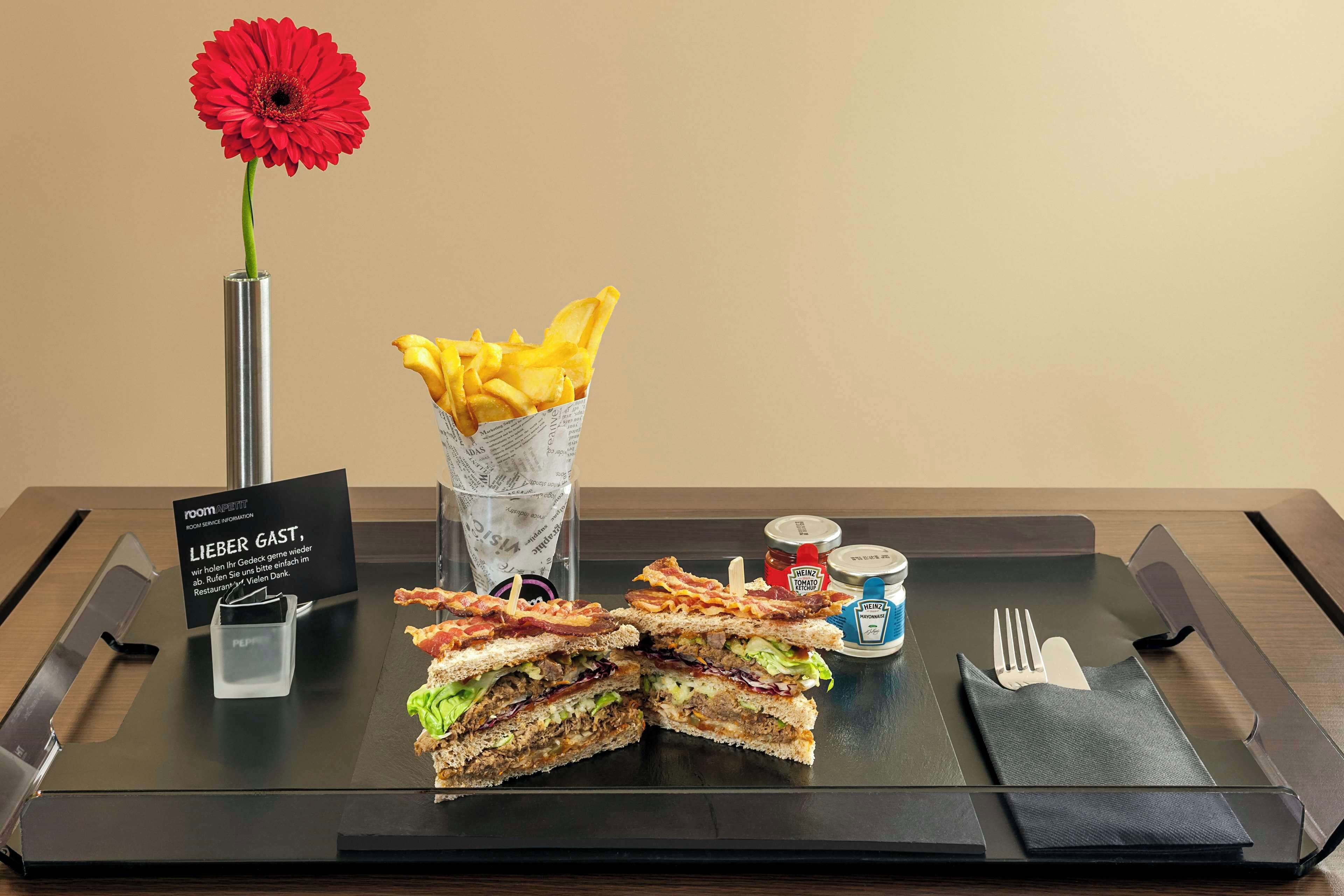 A breakfast tray with a sandwich, fries, and condiments.
