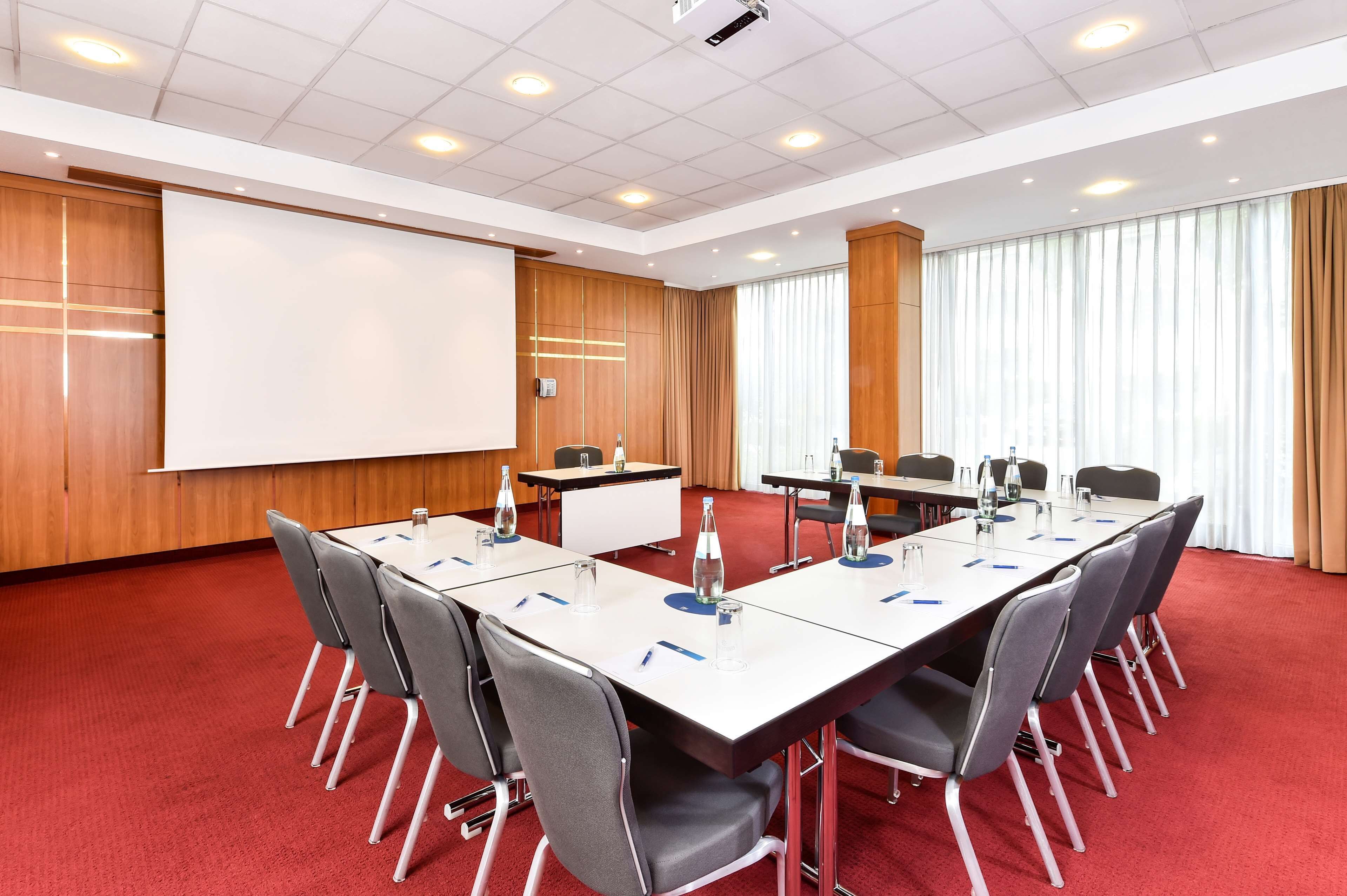 A conference room with a whiteboard, projector, and a large window with curtains.