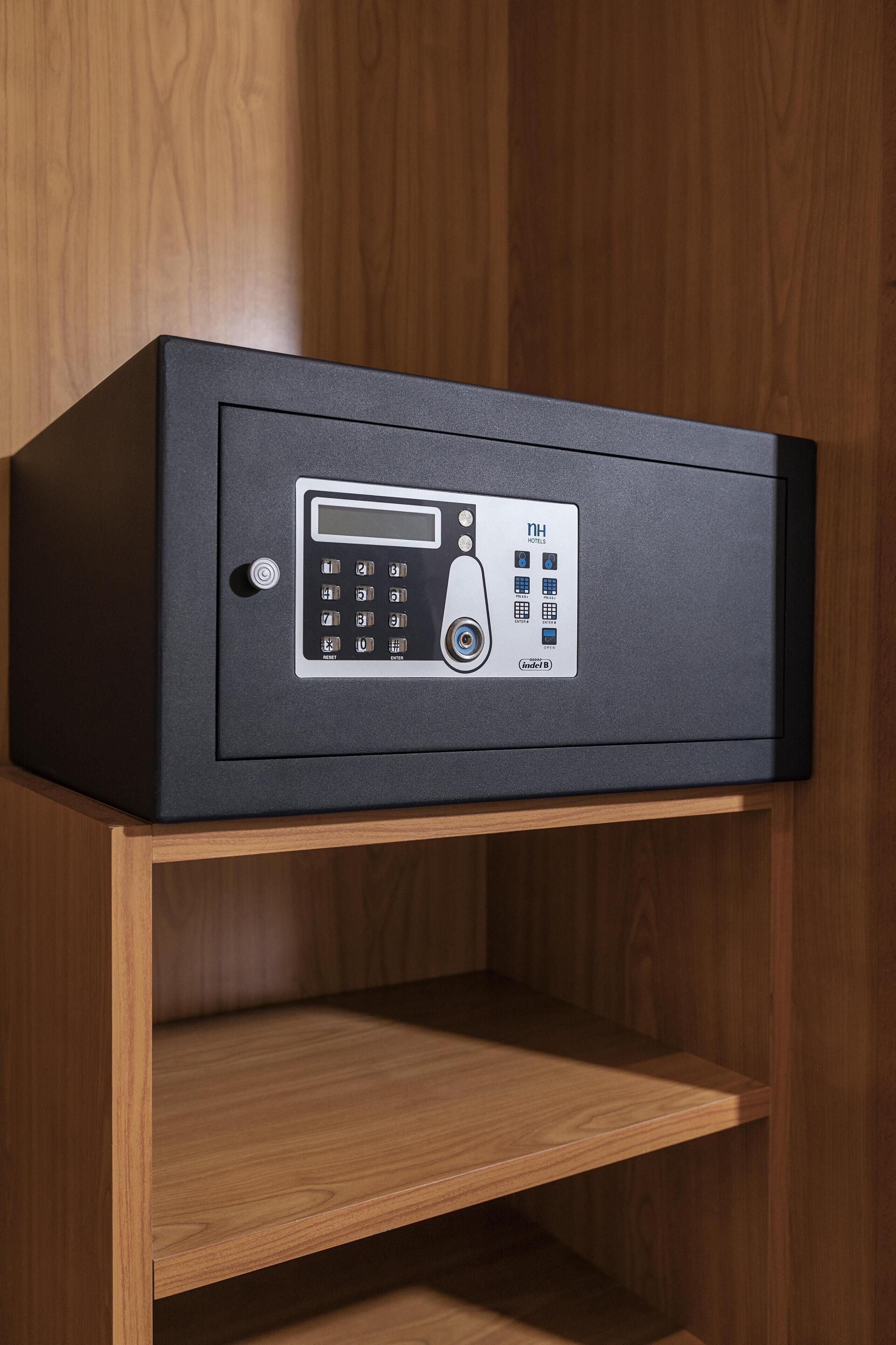 A black safe with a keypad, a lock, and a PIN entry slot, mounted on a wooden shelf.