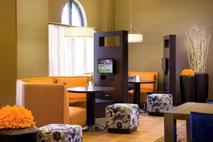 A modern hotel lobby with seating areas, a television, and decorative elements.