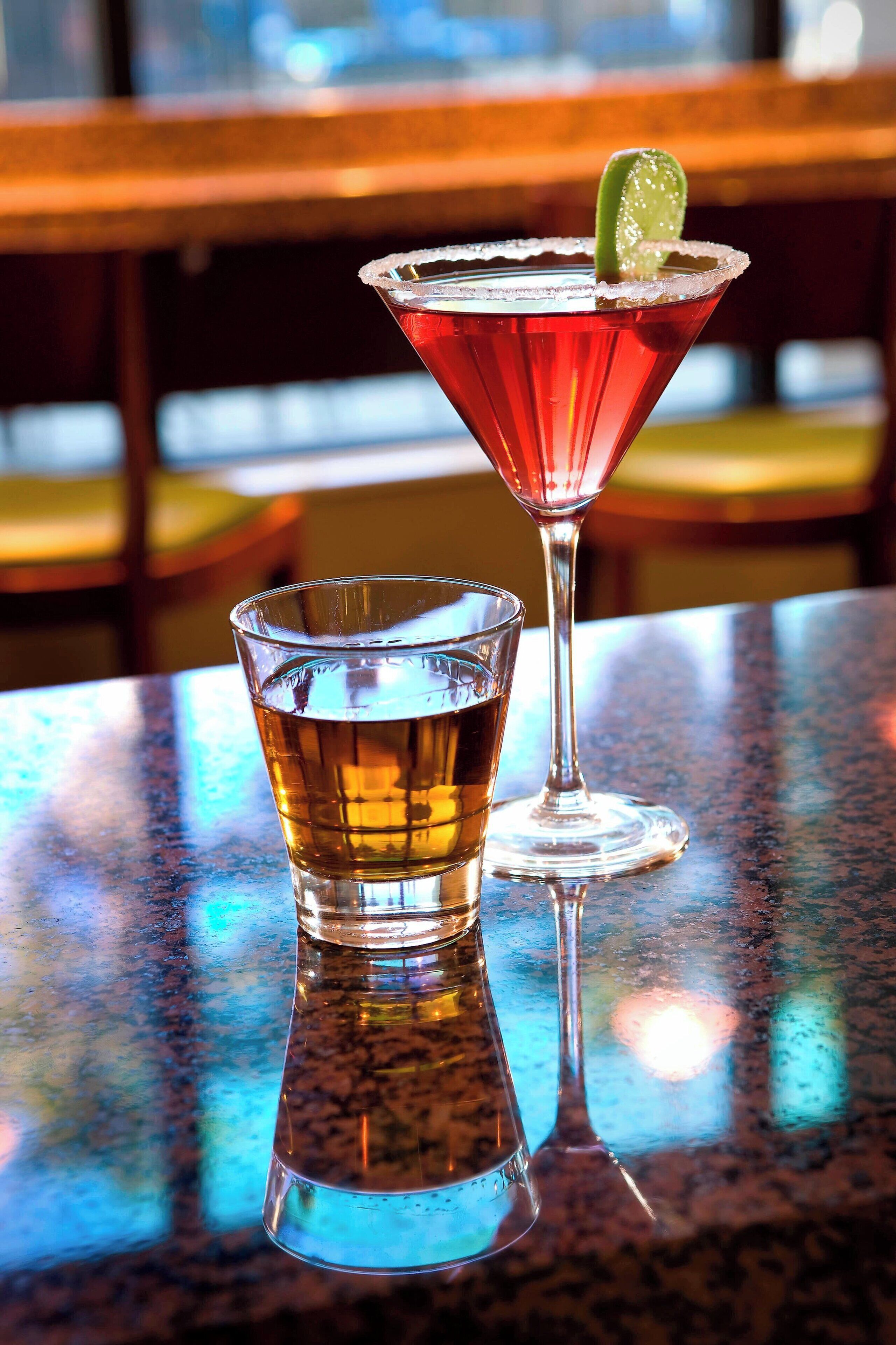 A martini glass with a lime garnish on a reflective surface.