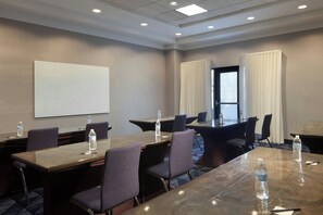 A conference room with a large table, chairs, a projector screen, and water bottles. - Courtyard by Marriott Newark Silicon Valley (Newark)