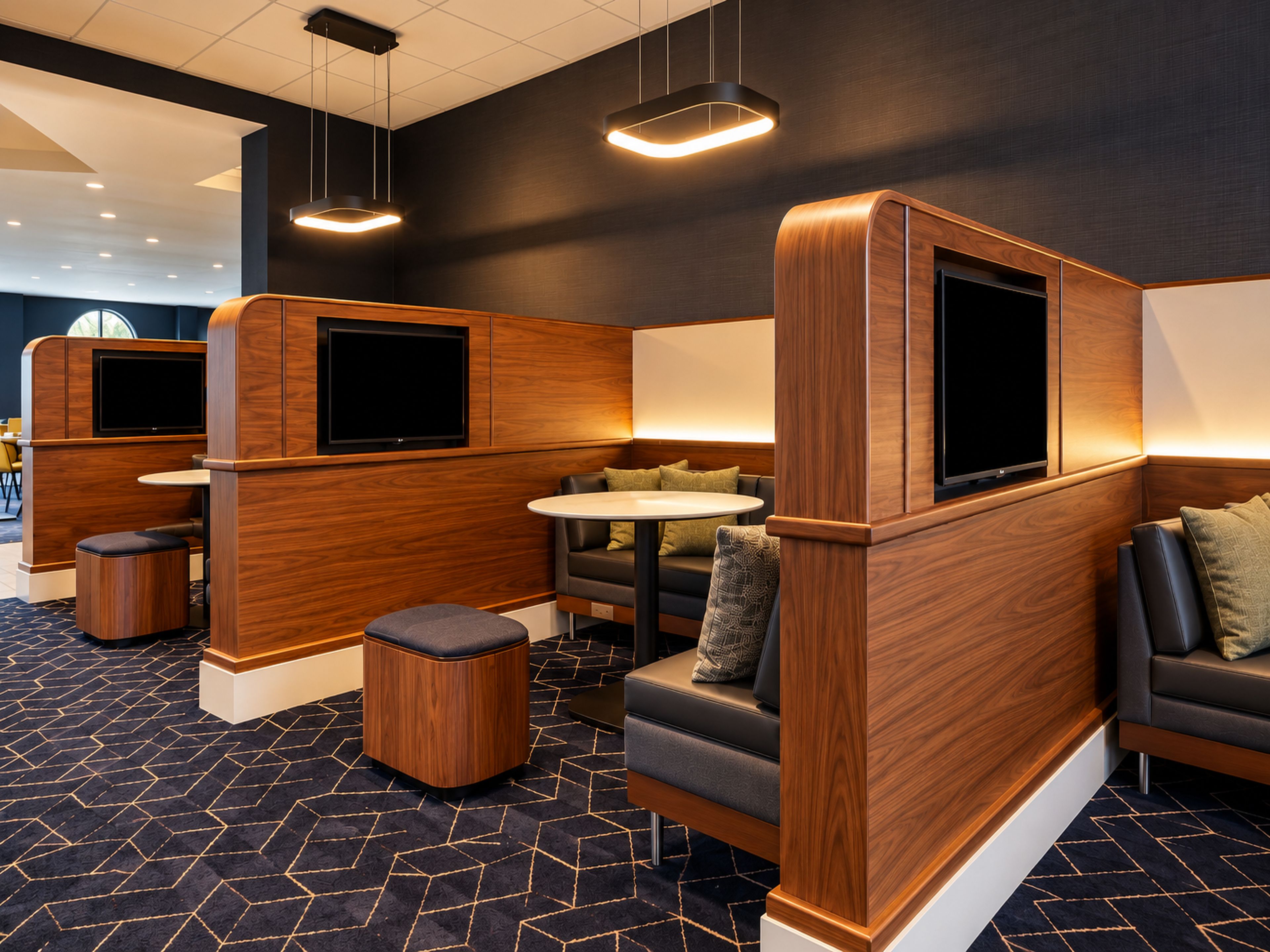 Une chambre d’hôtel moderne avec un canapé d’angle, une table ronde et un téléviseur à écran plat fixé au mur.