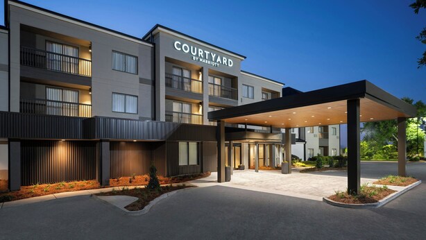 Un hotel de varios pisos con entrada cubierta y un letrero que dice 'Courtyard by Marriott'.