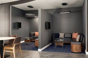A modern lounge area with a sofa, chairs, a table, and a TV mounted on the wall. - Courtyard by Marriott Valdosta (Valdosta)