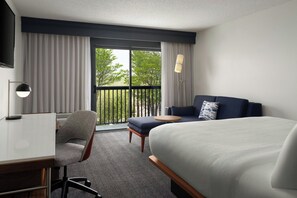 Une chambre dâhĂŽtel Ă©quipĂ©e dâun lit, dâun bureau, dâune chaise, dâun canapĂ©, dâun balcon et dâune tĂ©lĂ©vision.