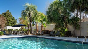 Una piscina con agua cristalina, rodeada de sillas de descanso y palmeras.