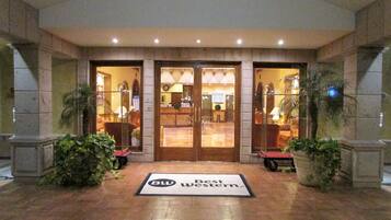 Entrada de un hotel con una recepción, un letrero que dice "Best Western" y un felpudo.