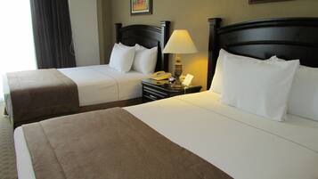 A hotel room with two beds, a nightstand with a lamp, and a painting on the wall.