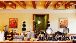 A buffet setup with various food items and beverages, a vase with flowers, and two paintings on the wall. - Best Western Hotel Posada Del Rio Express (Torreón)