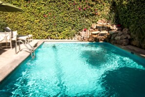 Relax by the pool surrounded by lush greenery and a soothing waterfall.