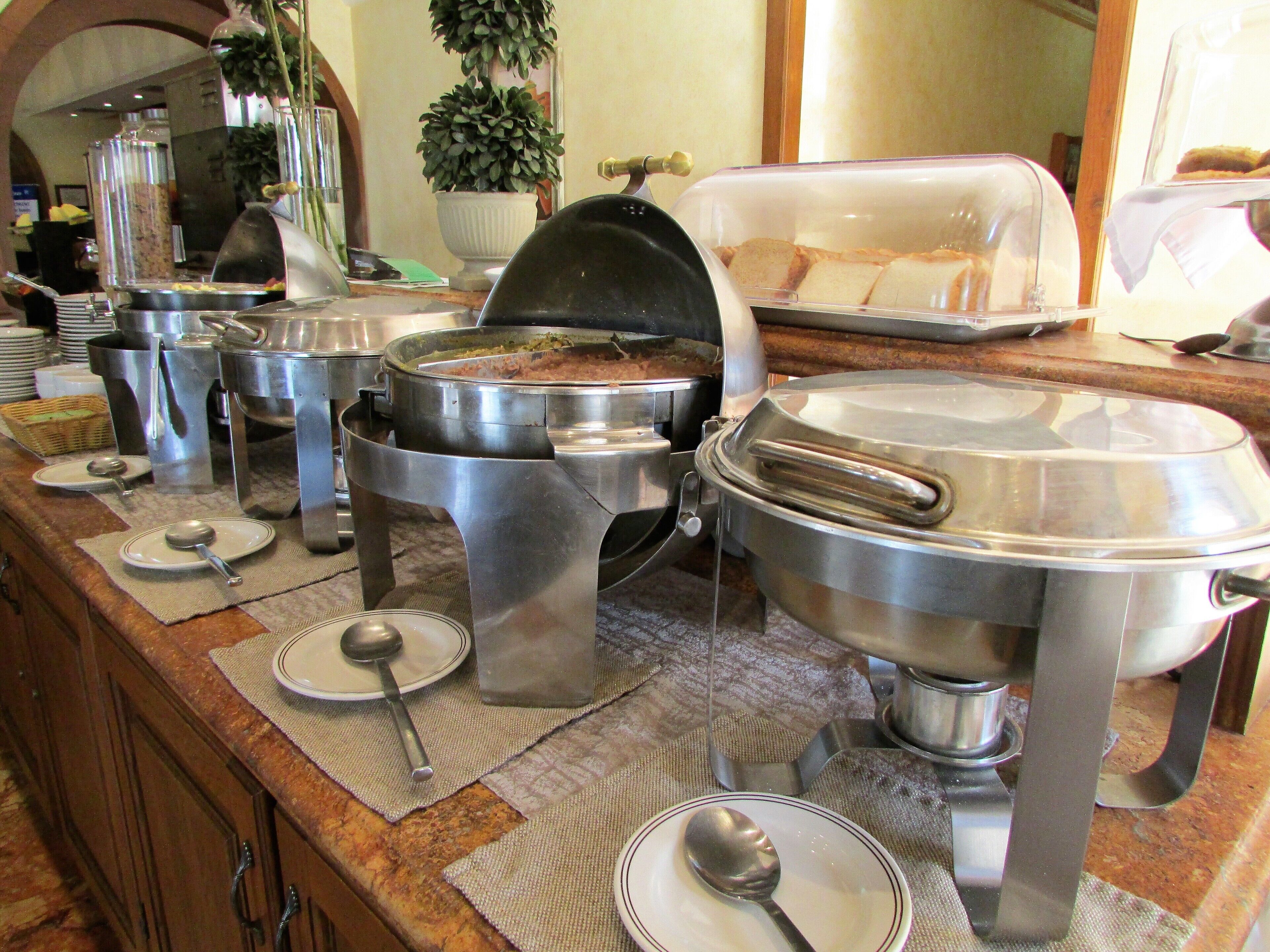 A buffet setup with various food containers and serving utensils.