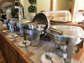 A buffet setup with various food containers and serving utensils.