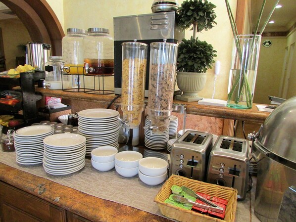 A buffet setup with various food containers, plates, and utensils.