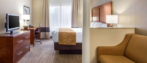 Ein Hotelzimmer mit einem Bett, einem Fernseher, einem Schreibtisch, einem Stuhl, einer Couch und einer Lampe.