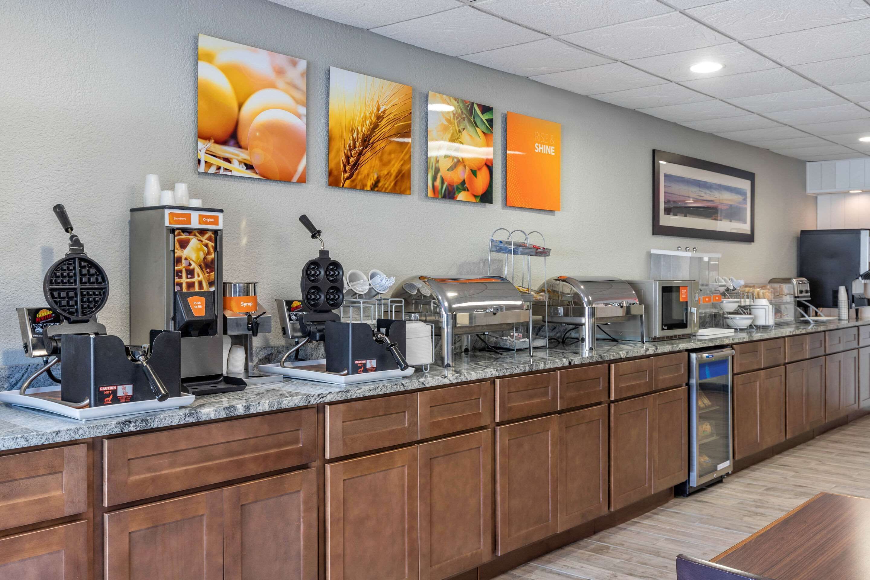 A breakfast bar with waffle makers, coffee machines, and a refrigerator.