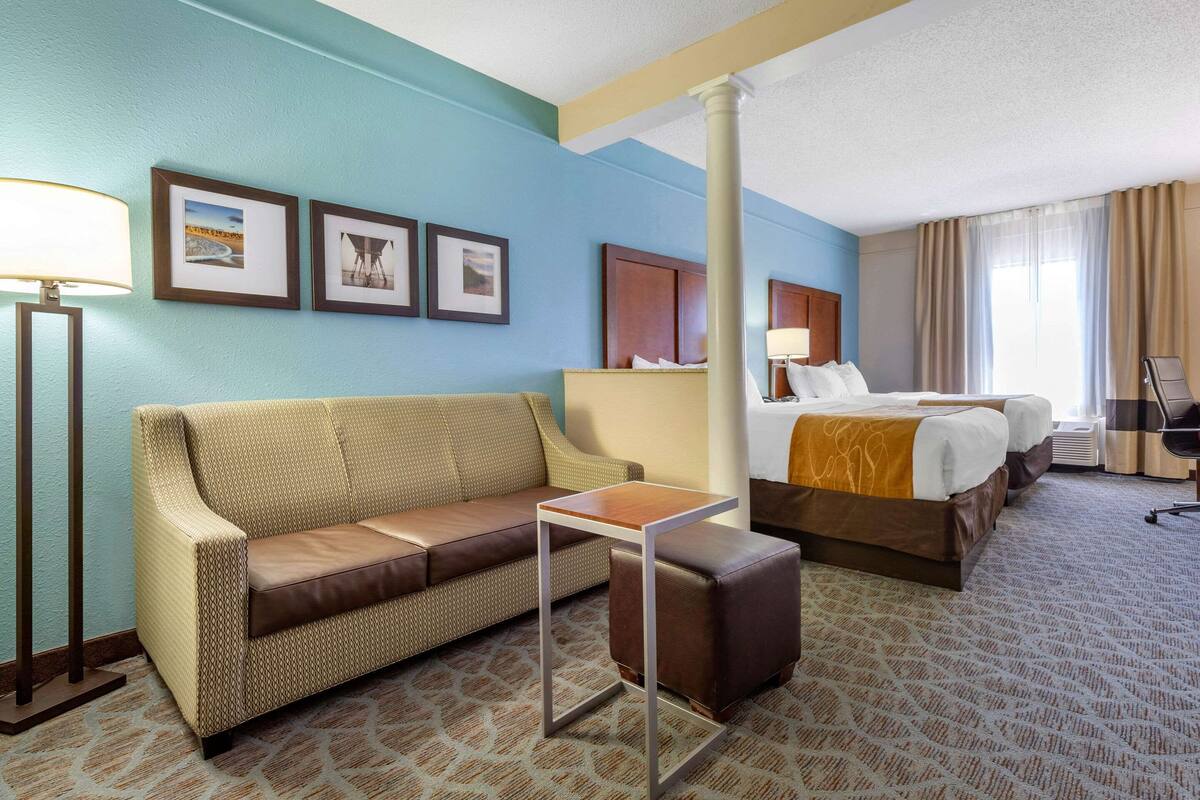 Habitación de hotel con sofá, una mesita, cama y mesita de noche.