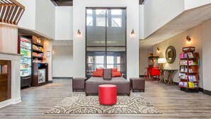 A spacious hotel lobby with a large bed, a red ottoman, and a vending machine. - Comfort Suites Southport - Oak Island (Southport)