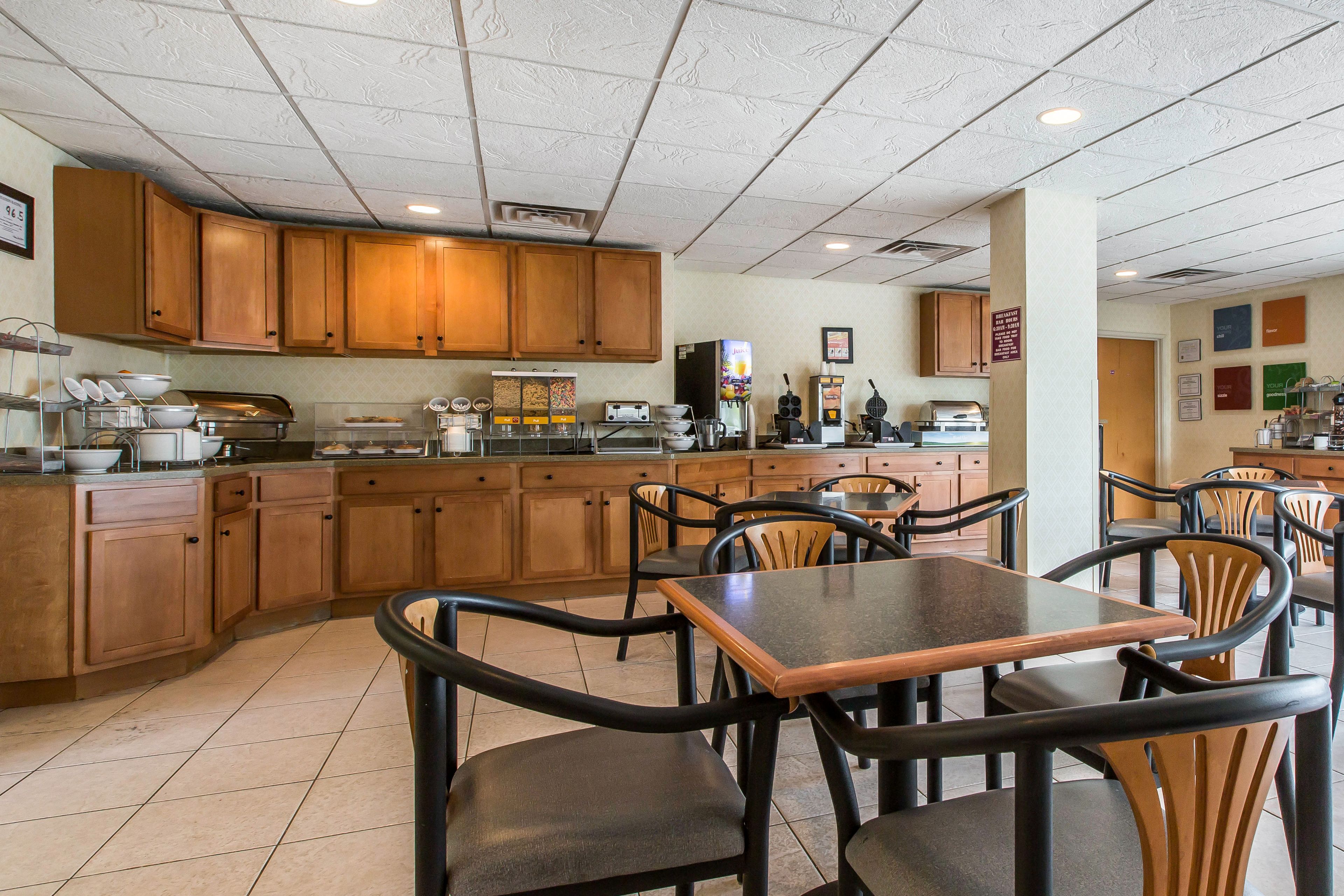 A restaurant with wooden cabinets, a buffet setup, and several tables and chairs.