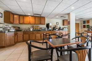 Un restaurante con armarios de madera, una barra de buffet y varias mesas y sillas.