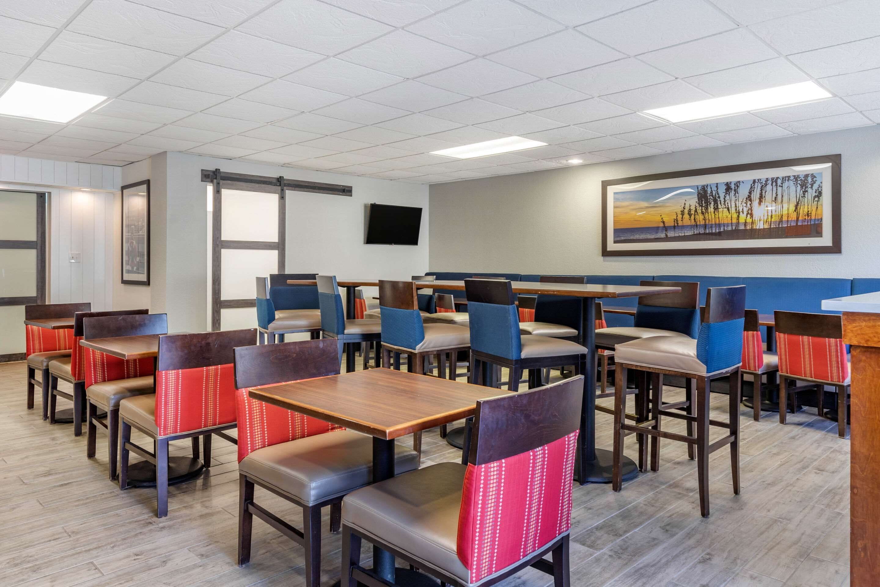 A restaurant with booths and tables, wooden flooring, and a painting on the wall.