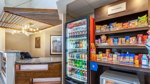 A reception area with a Coca-Cola refrigerator, snack shelves, and a small freezer. - Comfort Suites Southport - Oak Island (Southport)