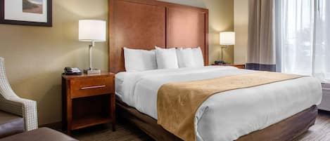 A hotel room with a large bed, two bedside tables, a chair, and a picture on the wall.