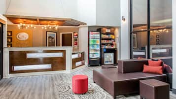A hotel lobby with a reception desk, seating area, and vending machines.