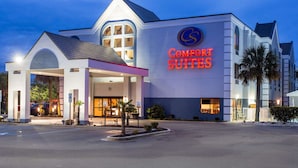 A hotel with a prominent "Comfort Suites" sign, a covered entrance, and a well-lit facade. - Comfort Suites Southport - Oak Island (Southport)