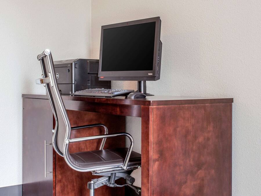 A modern desk with a computer, keyboard, and a chair.