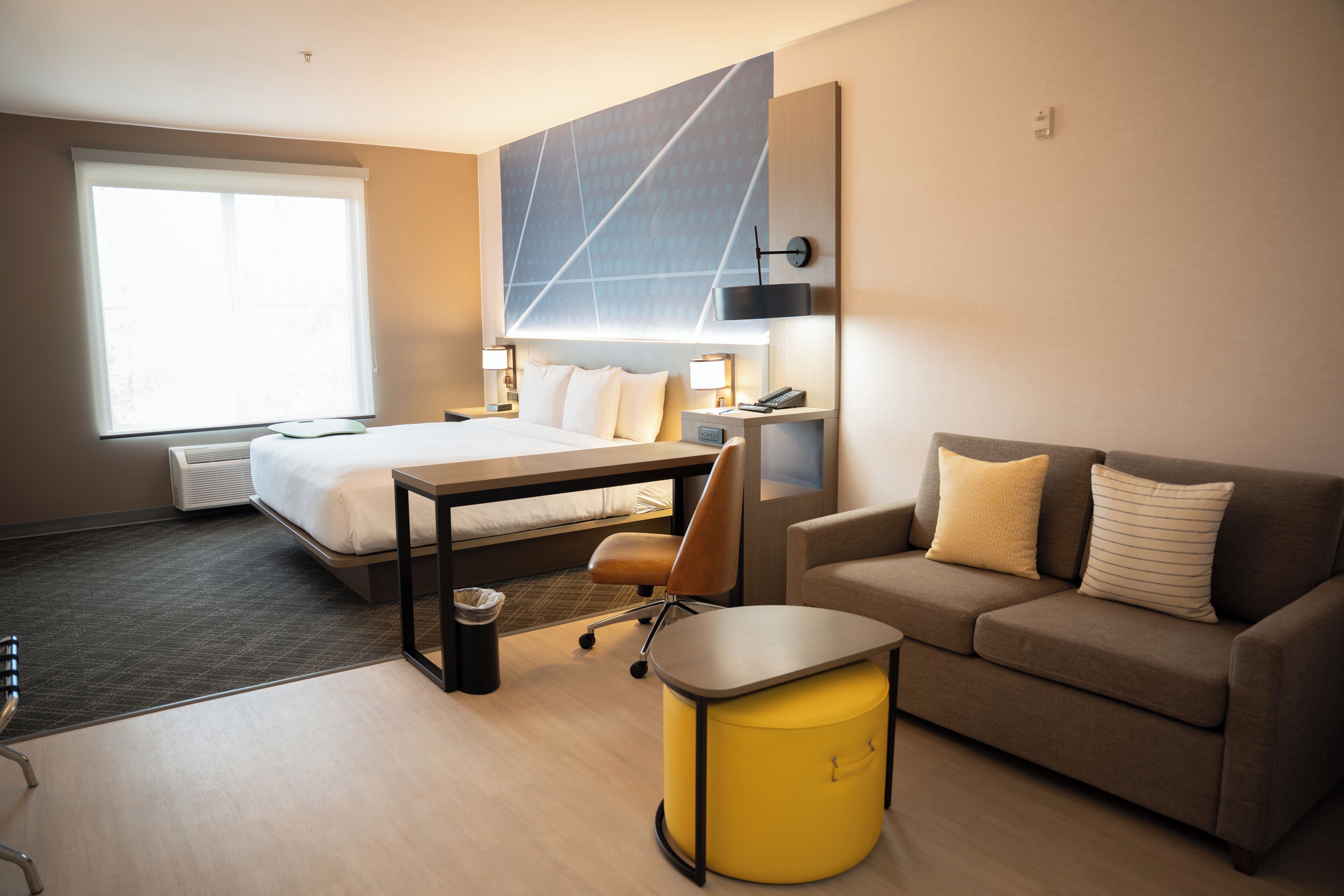 Habitació d'hotel amb llit, escriptori, sofà, cadira i paperera.