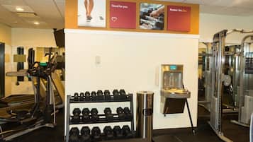 A gym with treadmills, dumbbells, and a water dispenser.