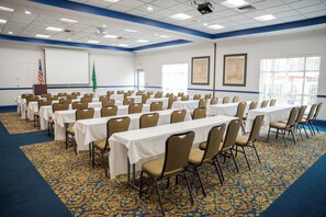 A conference room with rows of tables and chairs, a projector screen, and flags. - Comfort Suites Airport Tukwila Seattle (Tukwila)
