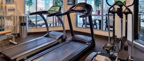 A gym with treadmills, elliptical machines, and a water dispenser.
