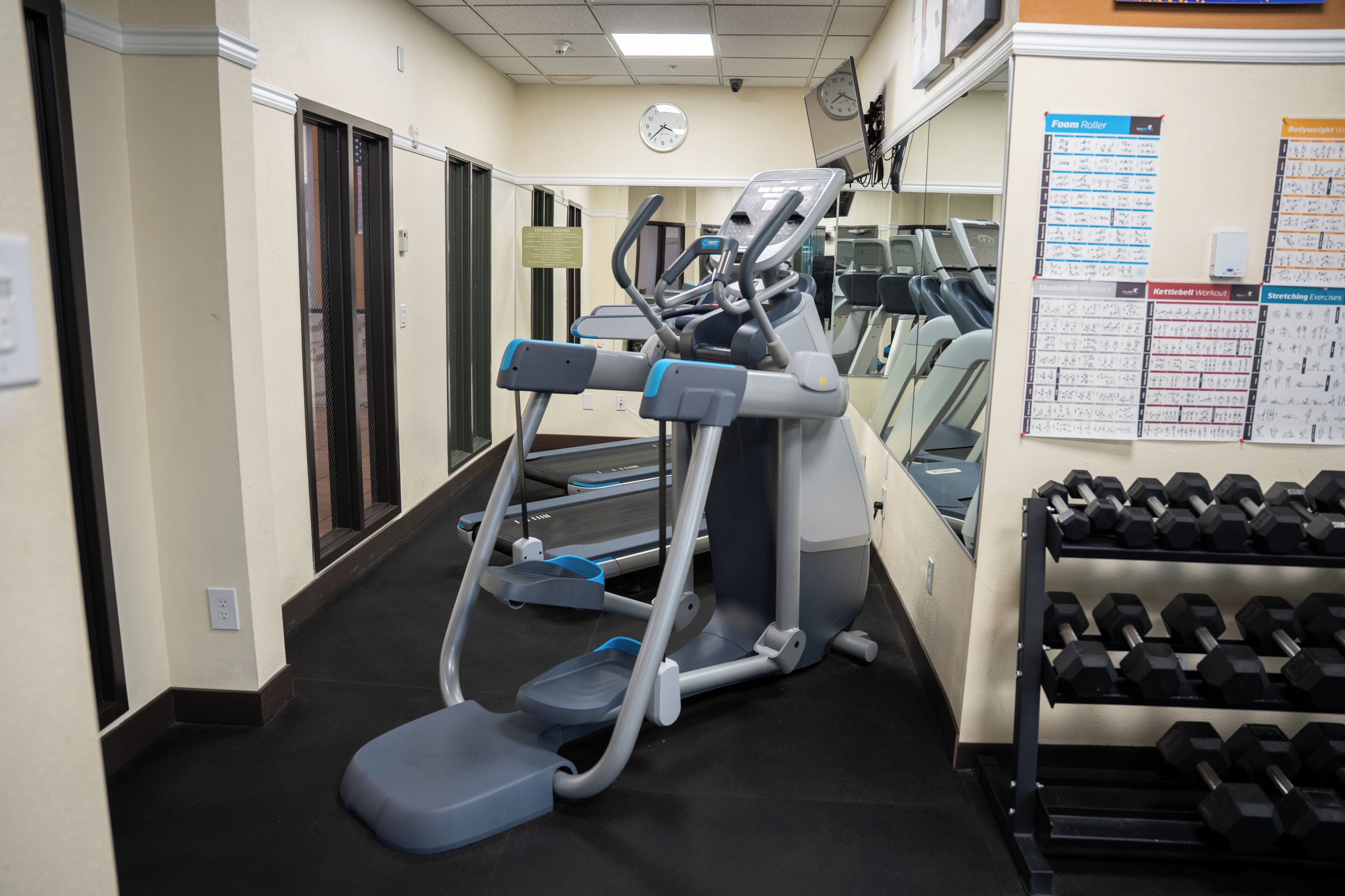 Ett gym med löpband, crosstrainers och ett ställ med hantlar.