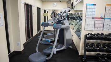 Ett gym med löpband, crosstrainers och ett ställ med hantlar.