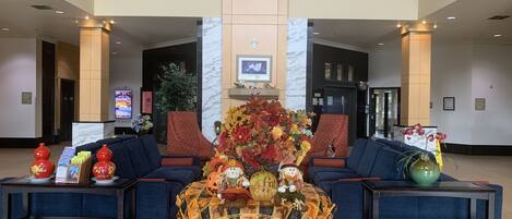 Un hall con dos sofás, una mesa con mantel temático de Halloween y un gran arreglo floral.