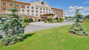 A Comfort Suites hotel with a central entrance, multiple floors, and a landscaped front yard with trees.