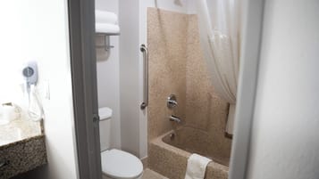 A bathroom with a toilet, a shower with a glass door, a towel rack, and a hairdryer on the counter.