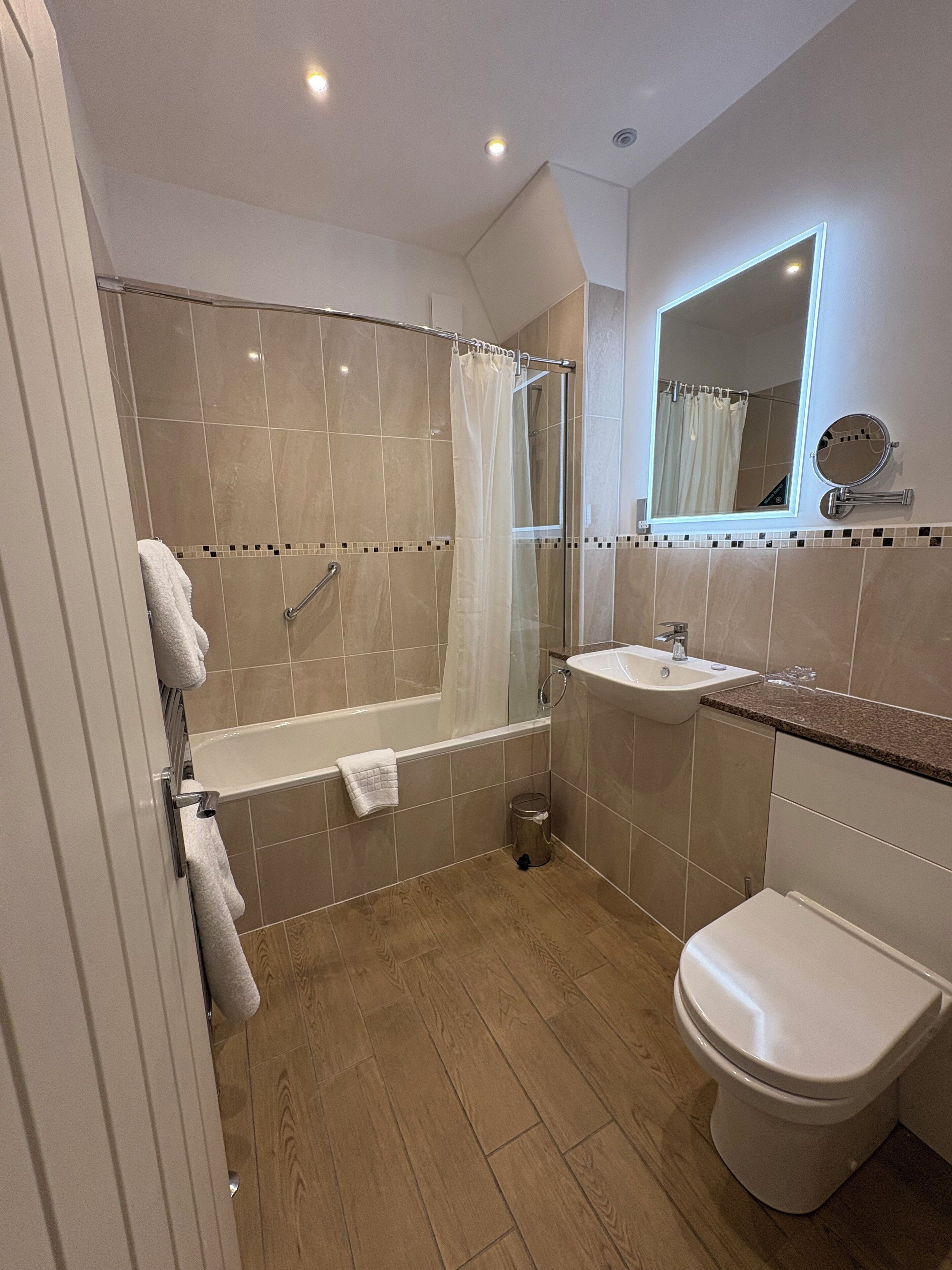 Une salle de bain moderne équipée d’une baignoire, d’une douche, d’un lavabo et de toilettes.