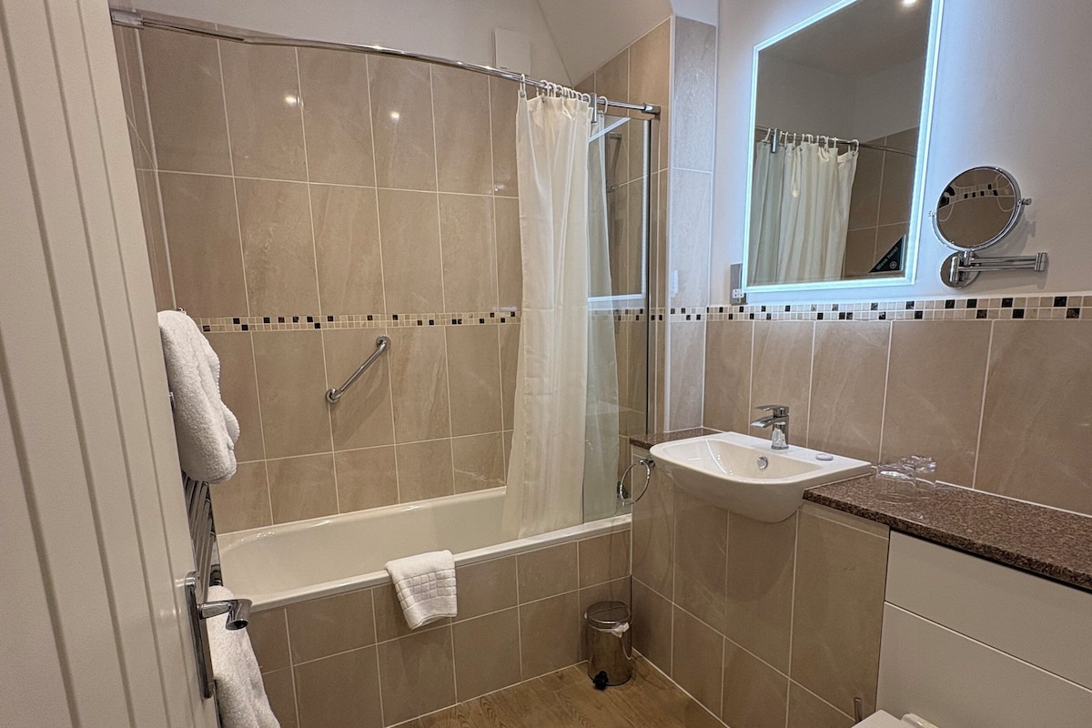 Un baño moderno con bañera, ducha, lavamanos e inodoro.