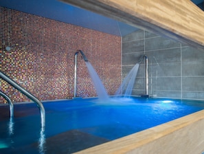 Ein Schwimmbecken mit einer gefliesten Wand und zwei Wasserstrahlen.
