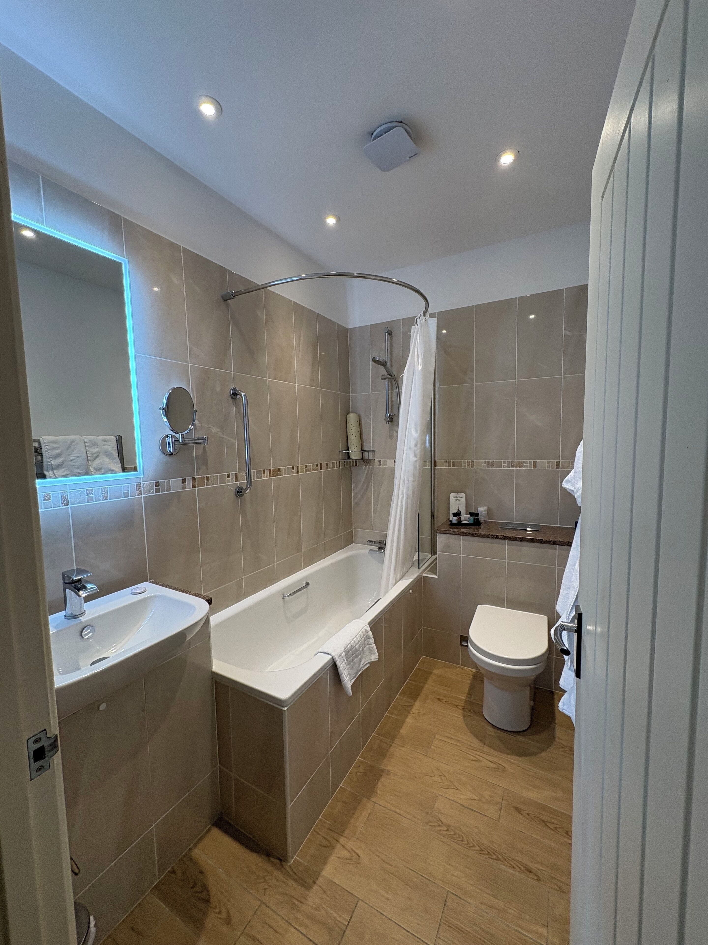 A modern bathroom with a bathtub, a sink, a toilet, and a shower area.