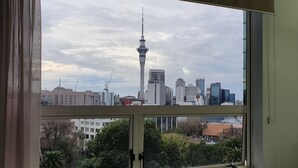 Vista urbana a través de una ventana, con una torre alta y edificios circundantes.