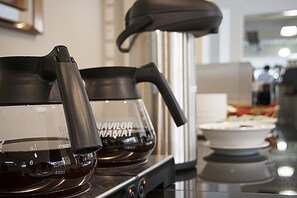 Eine Küche mit einer Kaffeemaschine und einem Glasbehälter auf der Arbeitsfläche.