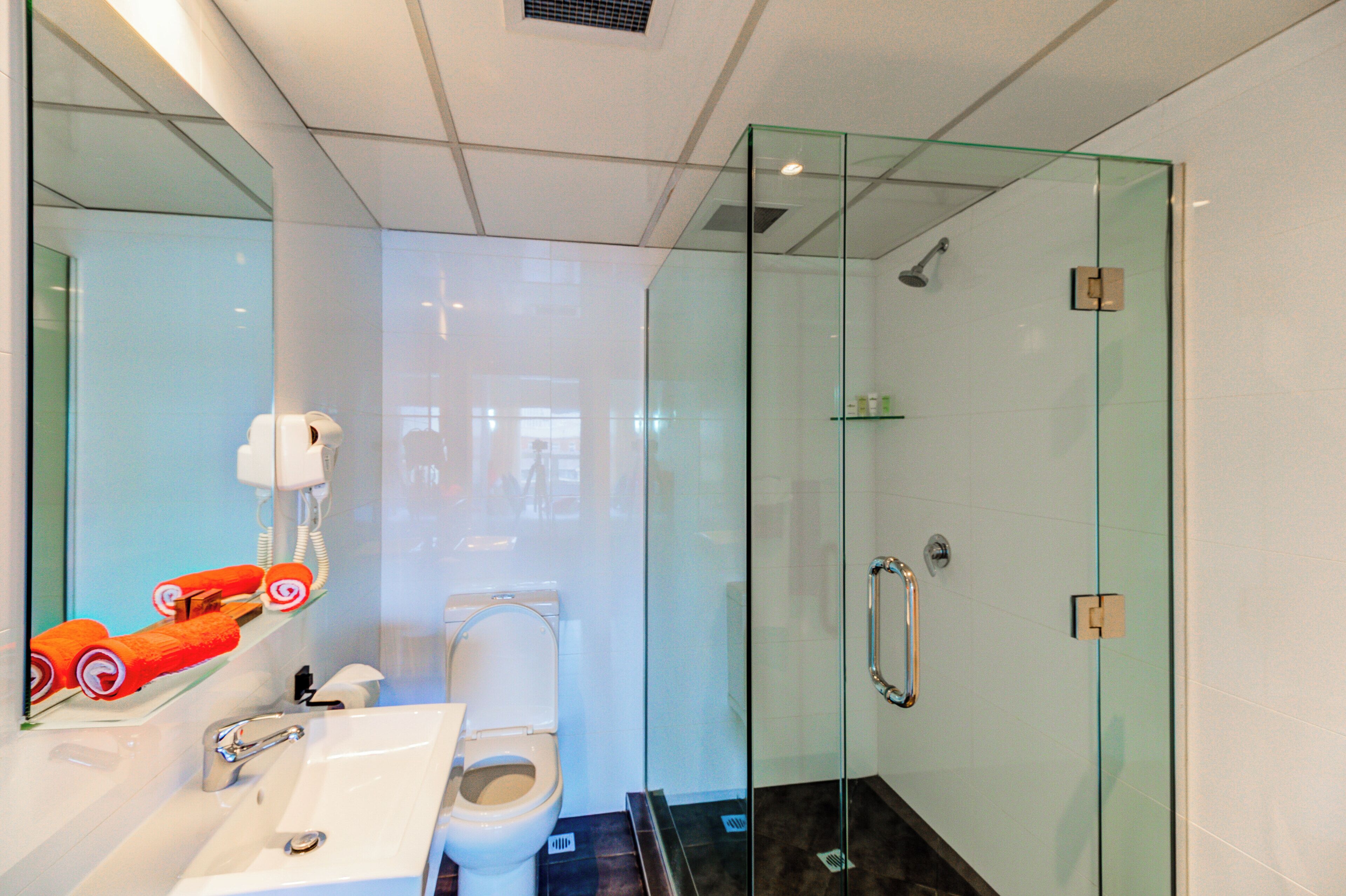 Ein modernes Badezimmer mit Duschkabine aus Glas, einem weißen Waschbecken und einer Toilette.