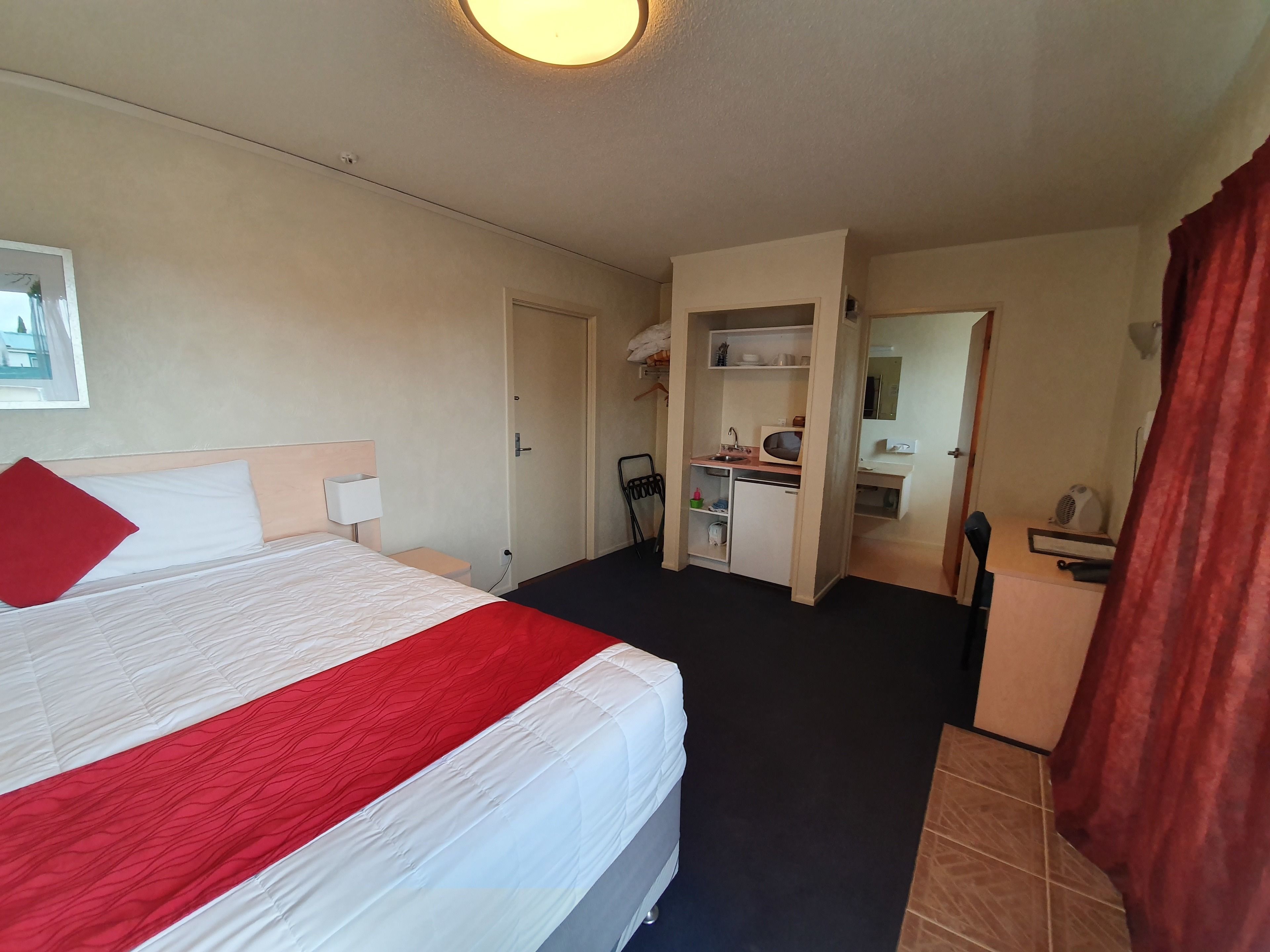 Et hotelværelse med seng, skrivebord, lille tekøkken og badeværelse.