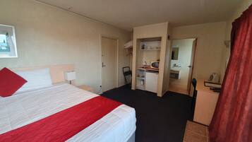 Et hotelværelse med seng, skrivebord, lille tekøkken og badeværelse.