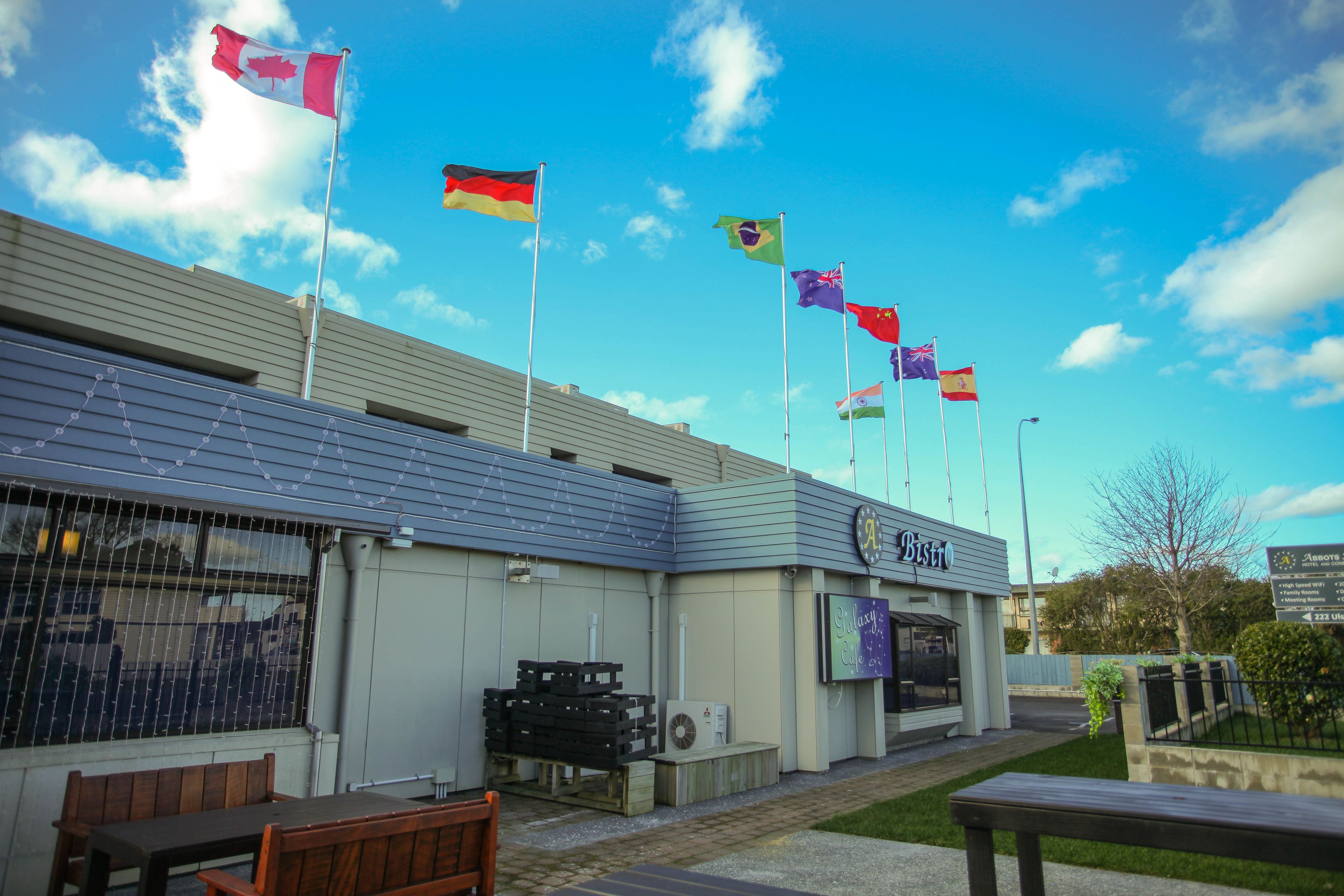 A building with multiple flags, a sign reading "Bistro", and outdoor seating.