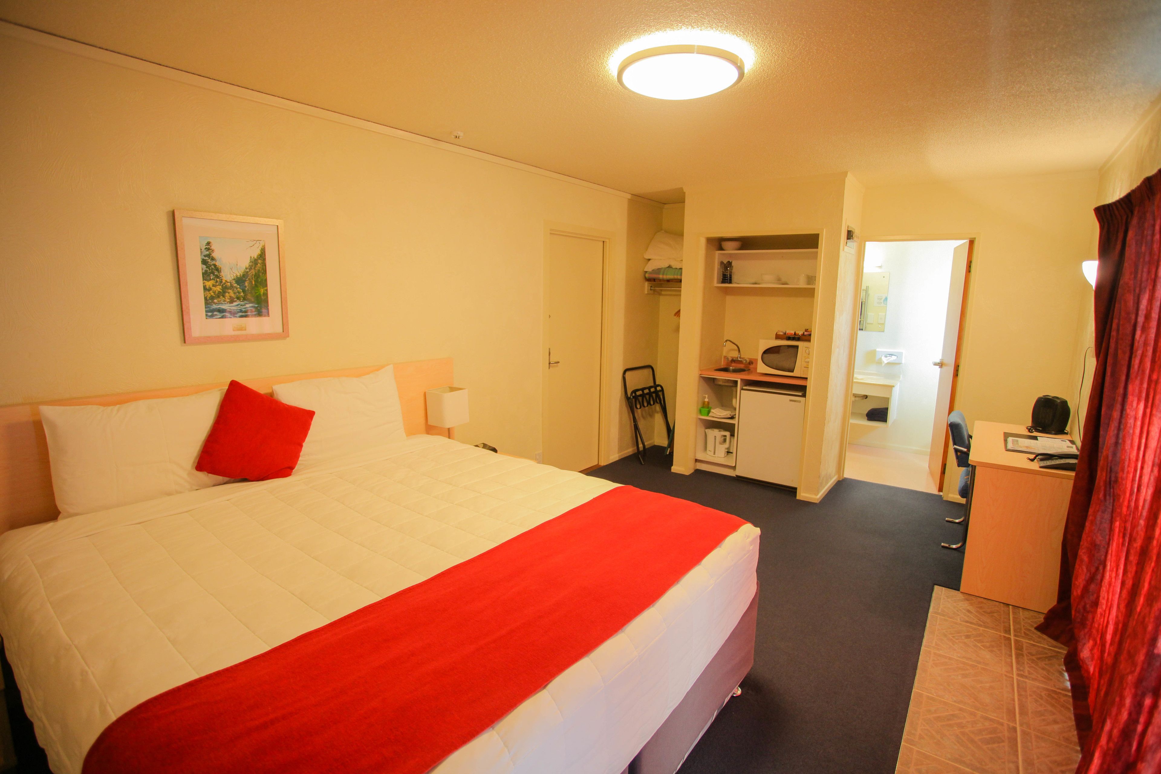 A hotel room with a large bed, a desk, and a chair.